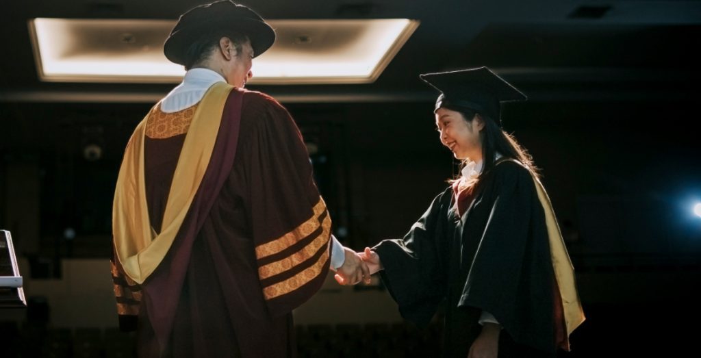 Graduation ceremony Asian Graduation university female student handshake with Dean on Auditorium stage