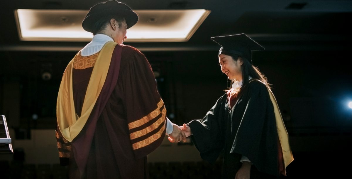 Graduation ceremony Asian Graduation university female student handshake with Dean on Auditorium stage